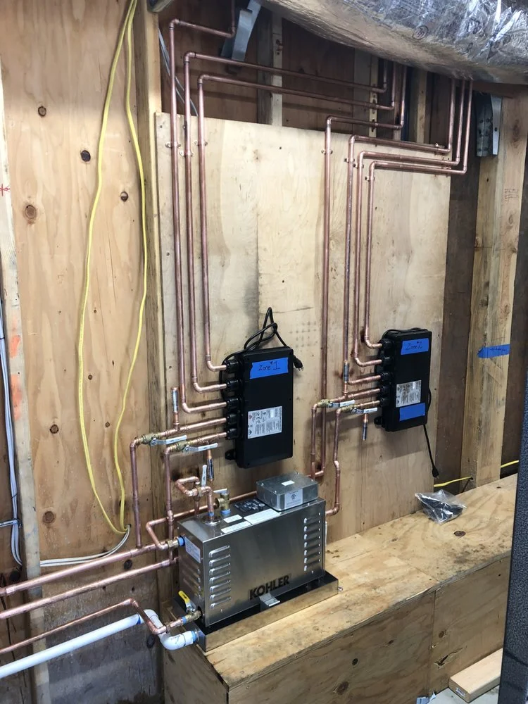 Dual Kohler tankless water heaters with copper piping and wall-mounted control units